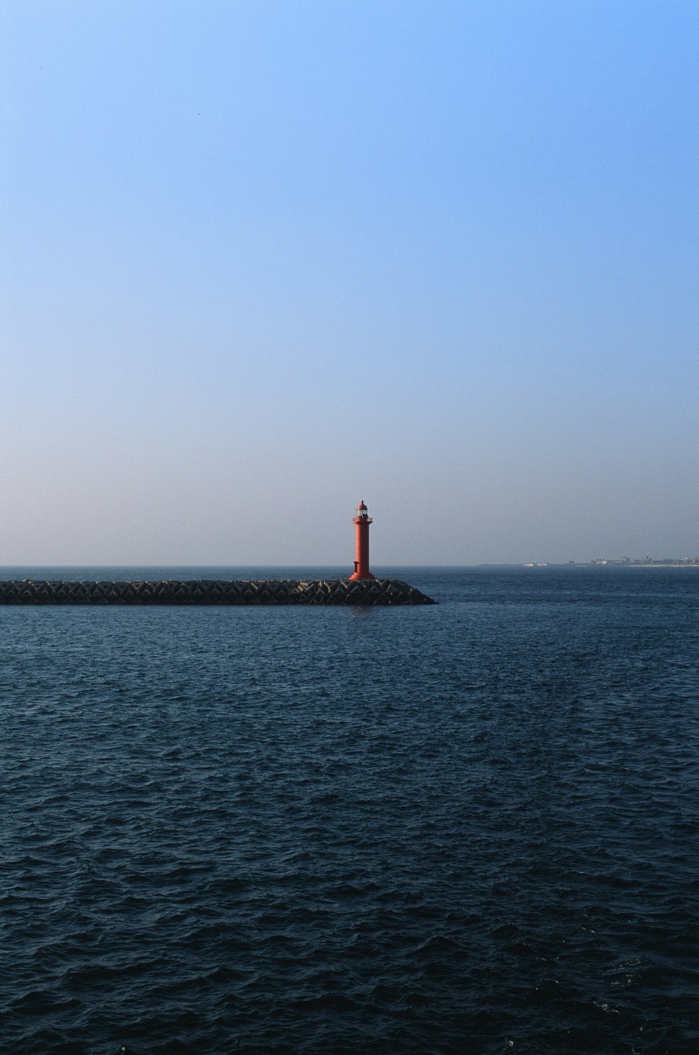 red and white lighthouse on the sea during daytime