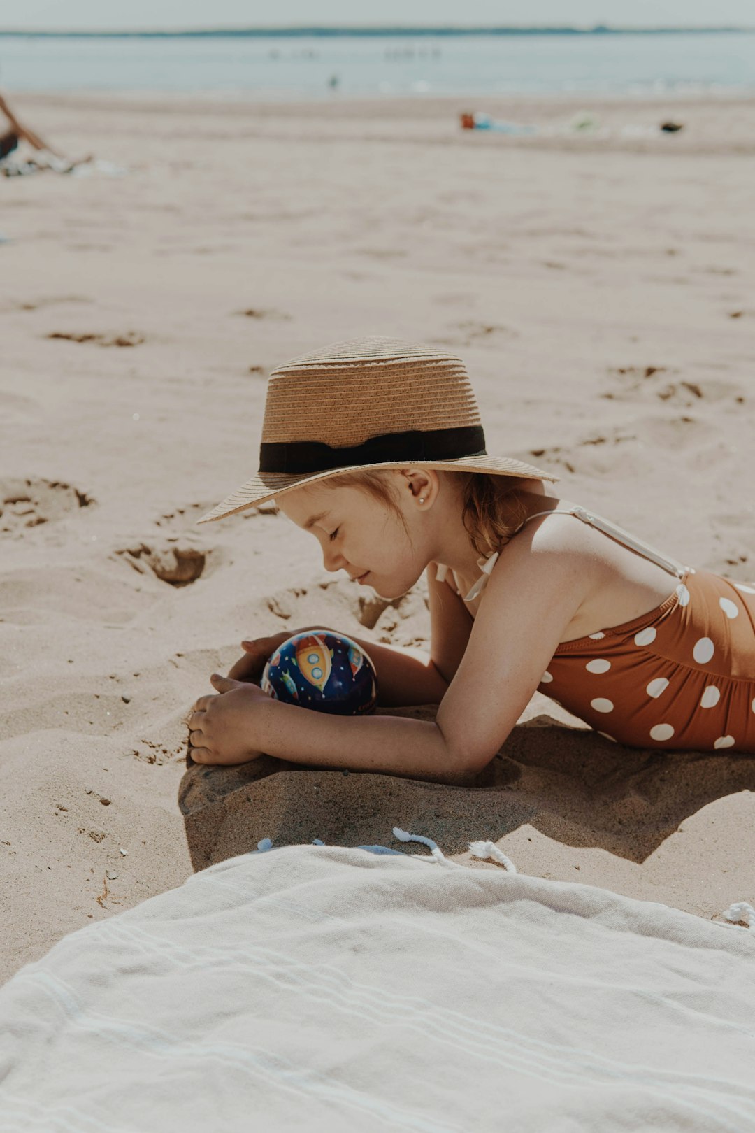 woman in white and red polka dot bikini lying on sand during daytime