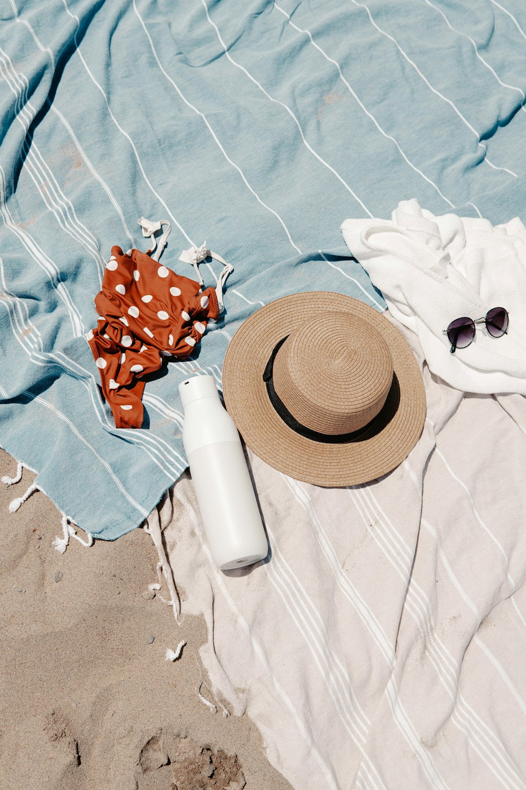 brown straw hat and white plastic bottle on blue textile
