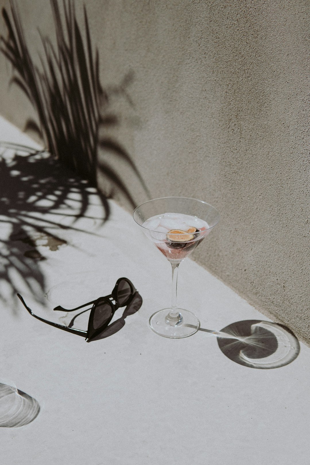 black framed sunglasses beside clear wine glass on white table