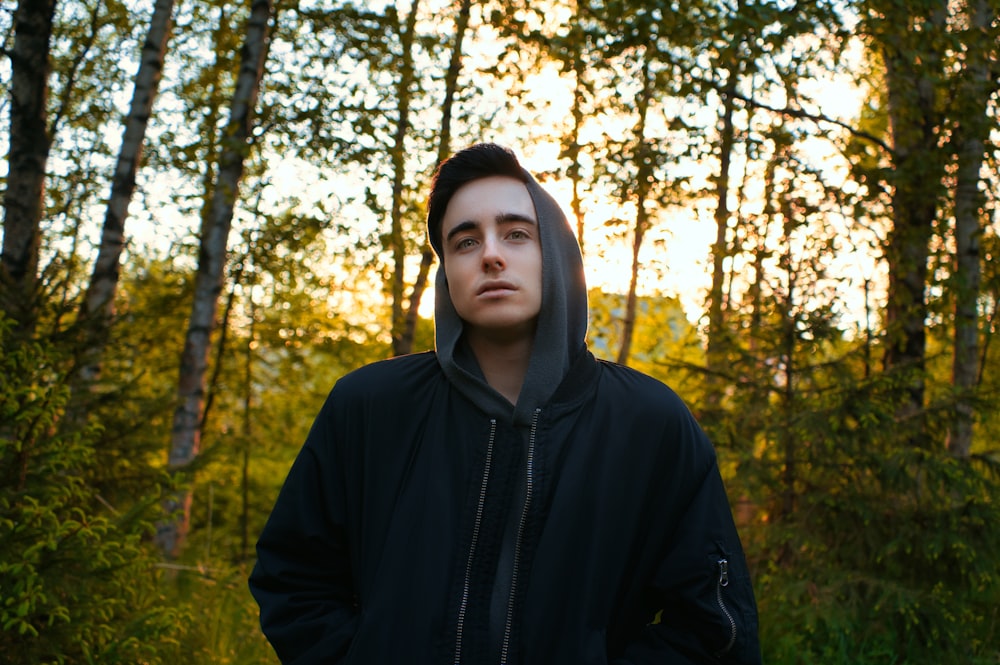 man in black hoodie standing in forest during daytime
