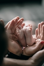 Hands gently holding a tiny baby’s feet, symbolizing tender postpartum care and connection.