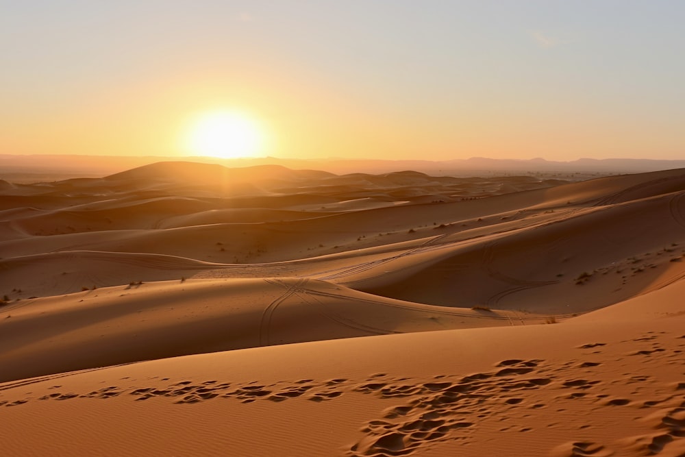 campo de areia marrom durante o pôr do sol