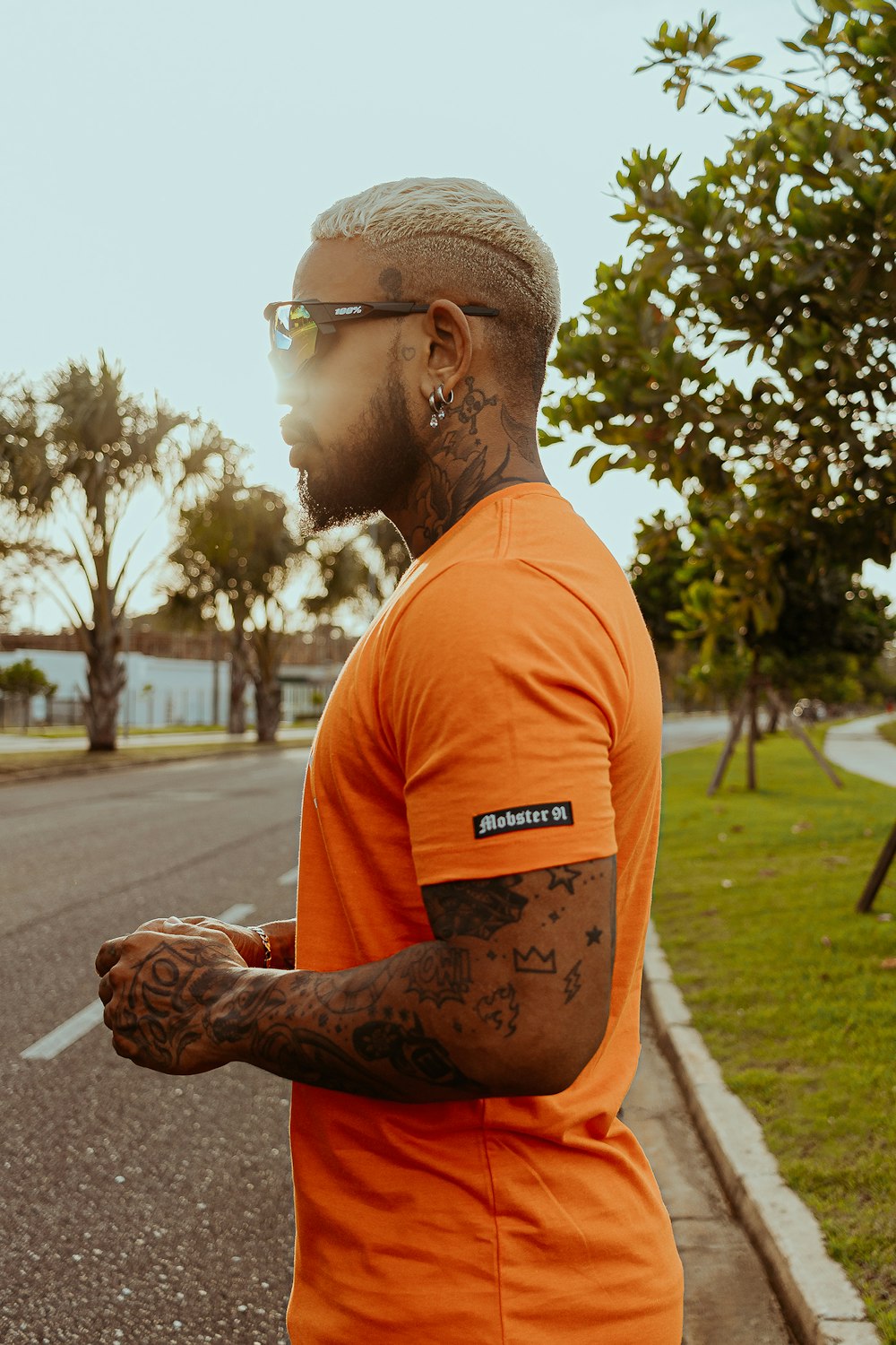 man in orange crew neck t-shirt with tattoo on his right arm