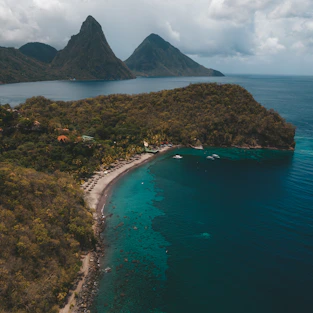 green and brown mountain beside blue sea under white clouds during daytime