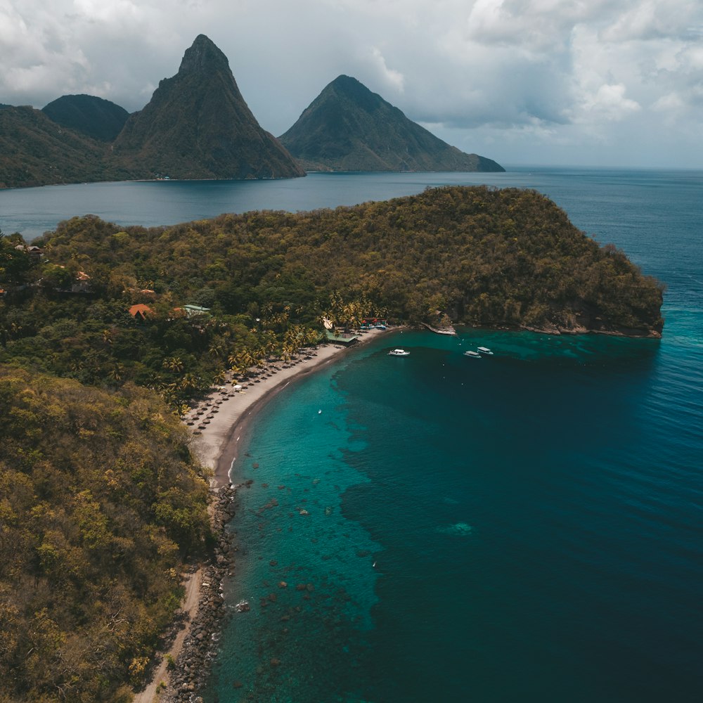 green and brown mountain beside blue sea under white clouds during daytime