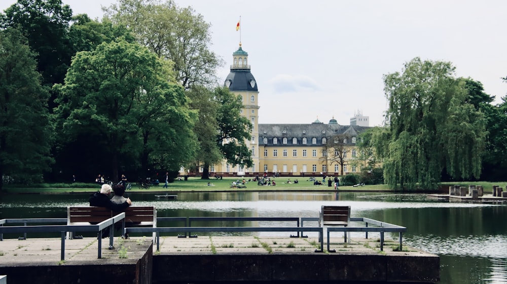 people sitting on bench near body of water during daytime