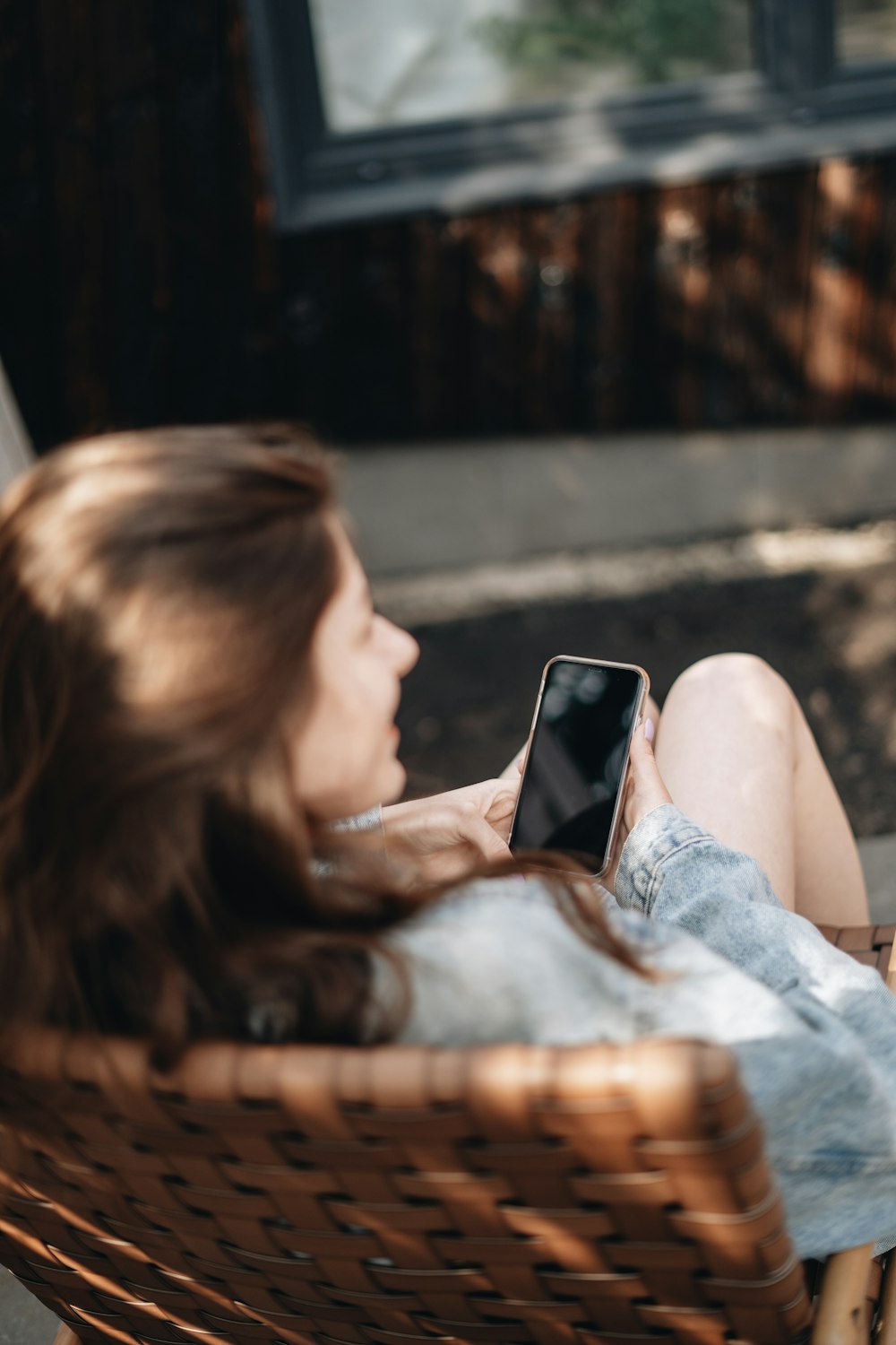 woman in white tank top lying on bed using black smartphone