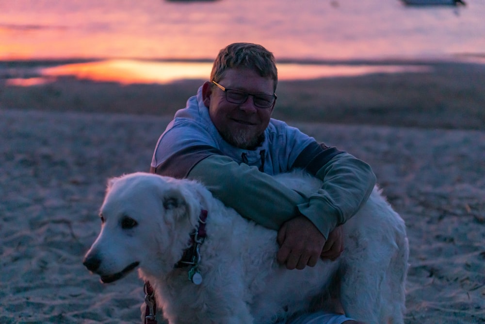 man in blue dress shirt hugging white short coated dog