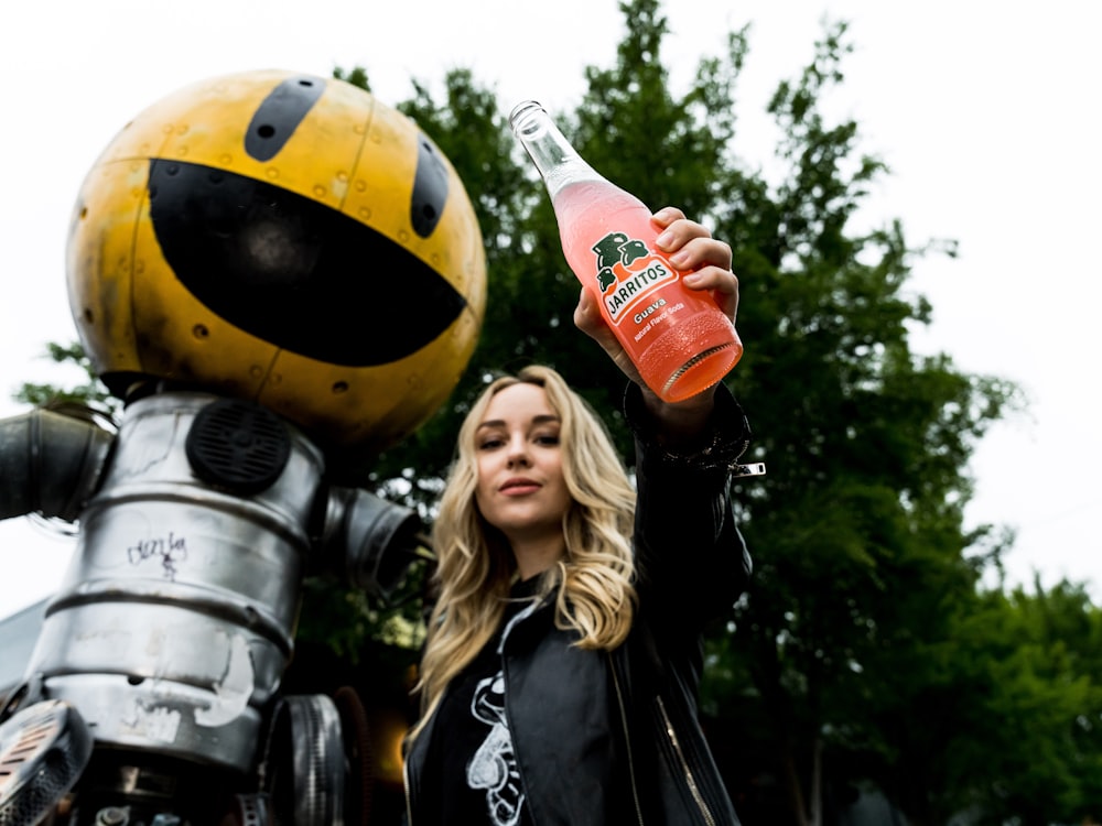 woman in black leather jacket holding orange plastic bottle