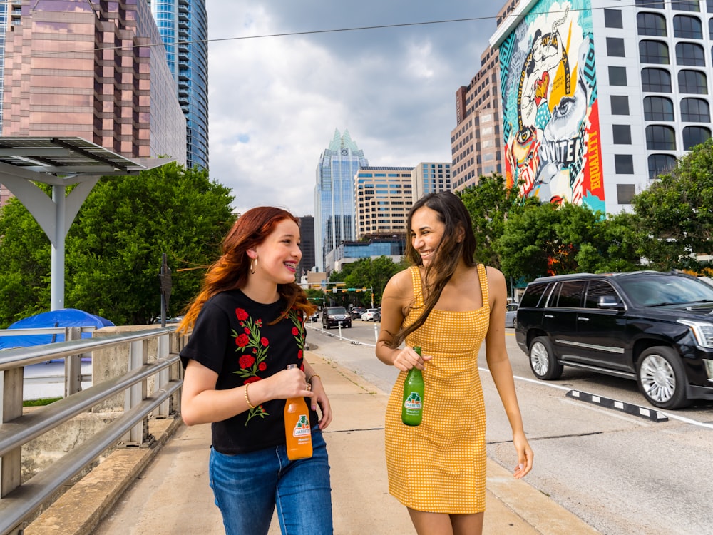 woman in black tank top and blue denim jeans standing beside woman in yellow tank top