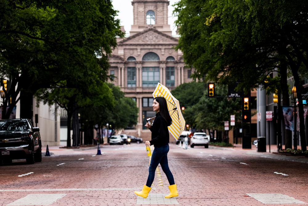 man in black and yellow jacket and black pants walking on sidewalk during daytime