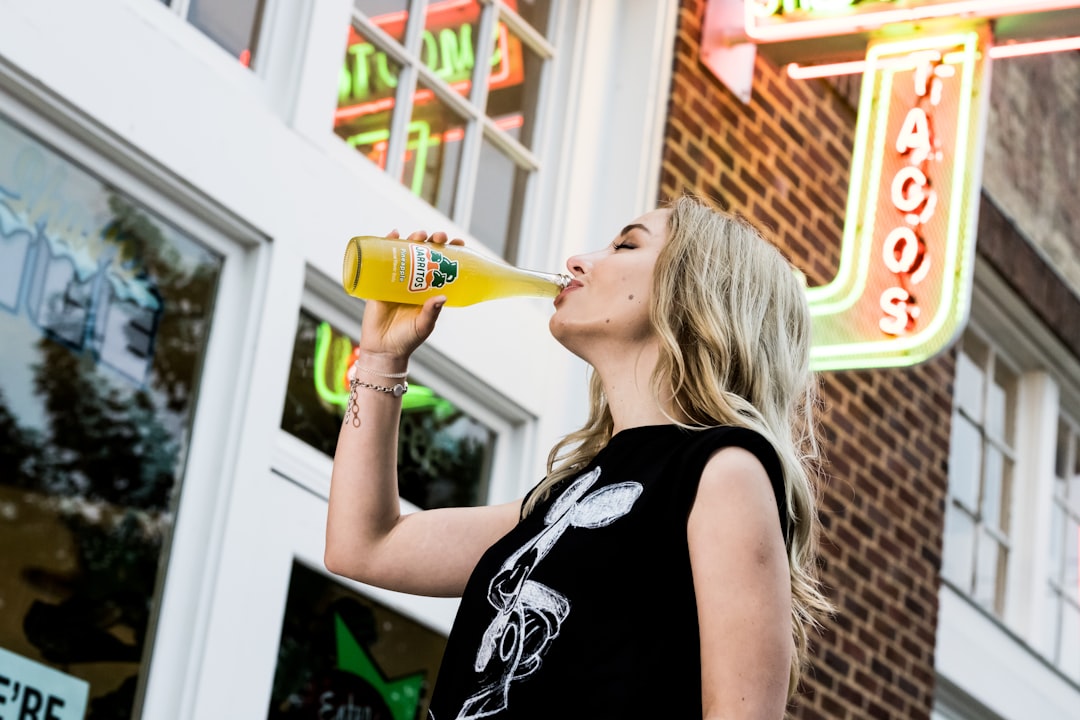 woman in black tank top drinking from clear glass bottle