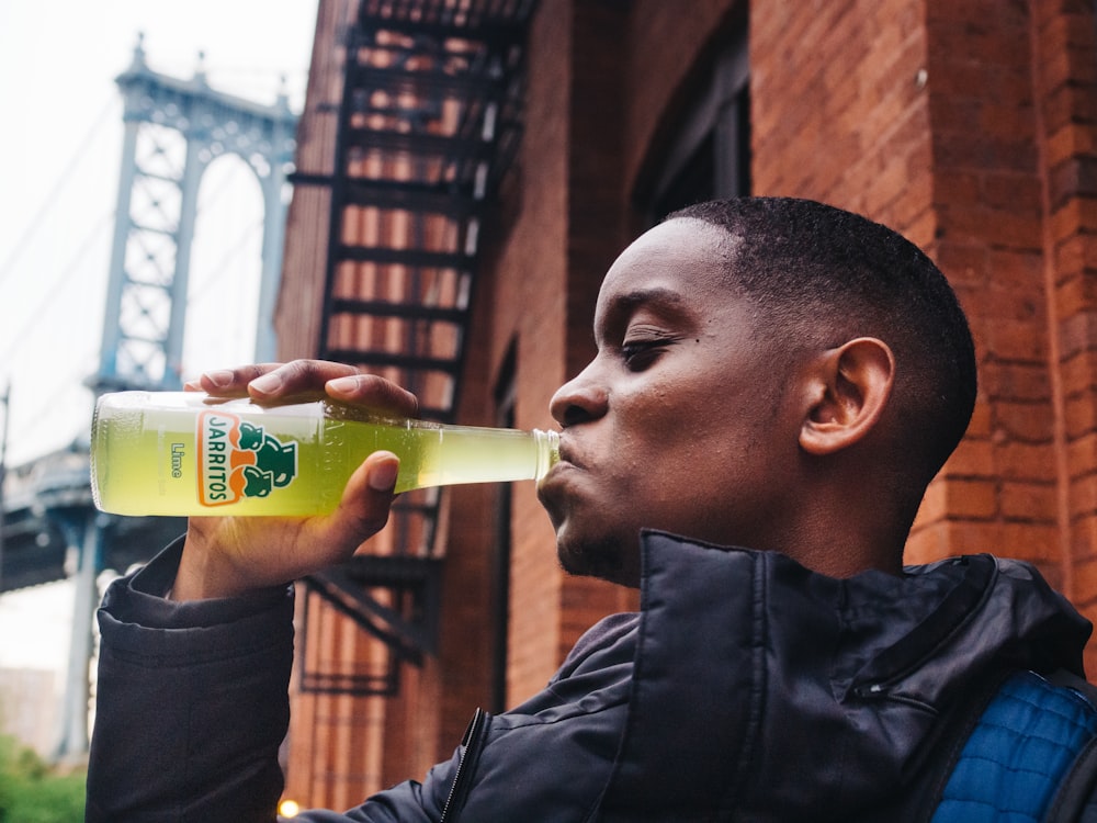 man in black leather jacket drinking yellow labeled bottle