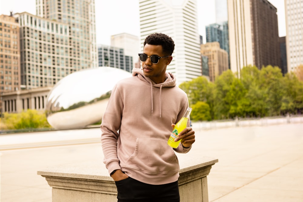 man in brown hoodie holding yellow and green bottle