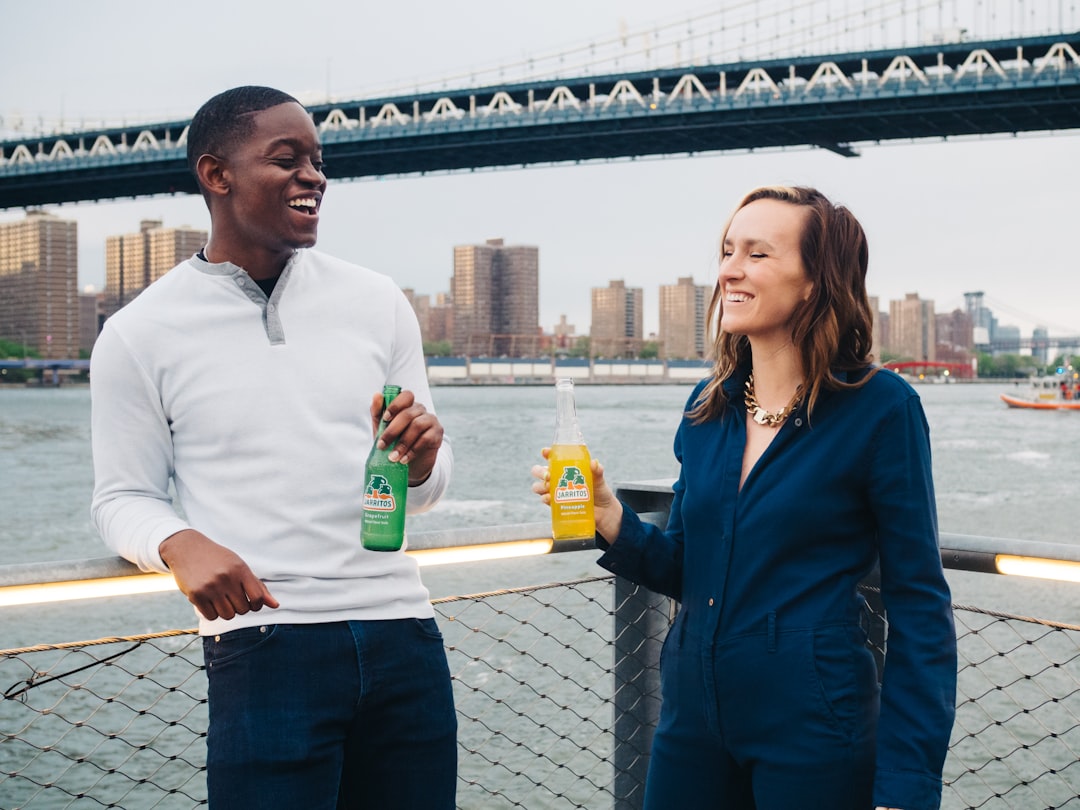 man in white crew neck shirt holding yellow plastic bottle beside woman in blue blazer