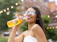 A smiling woman holding a chilled bottle of vivaburbuja soda outdoors on a sunny day.