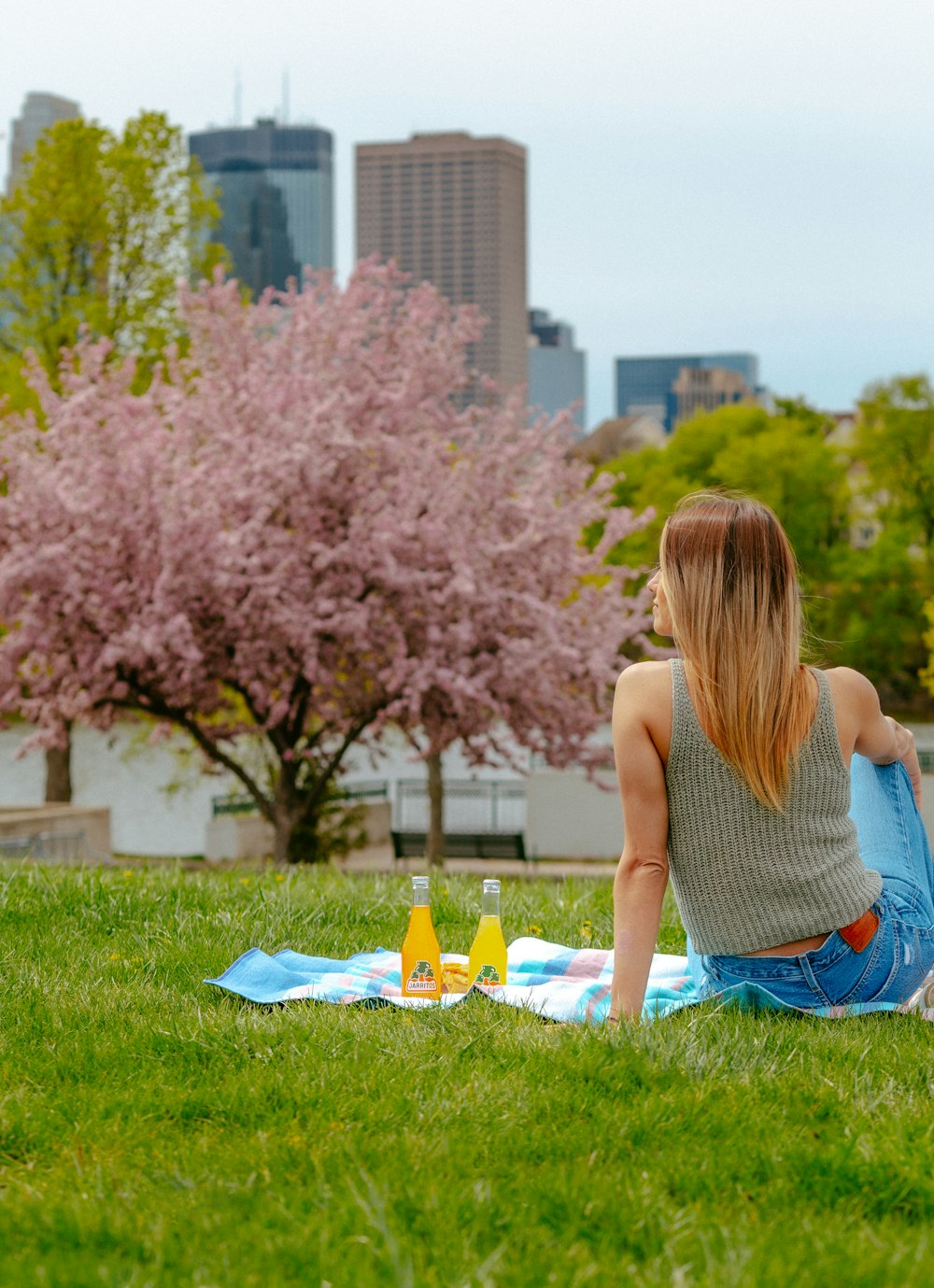 woman in gray tank top and blue denim shorts sitting on green grass field during daytime