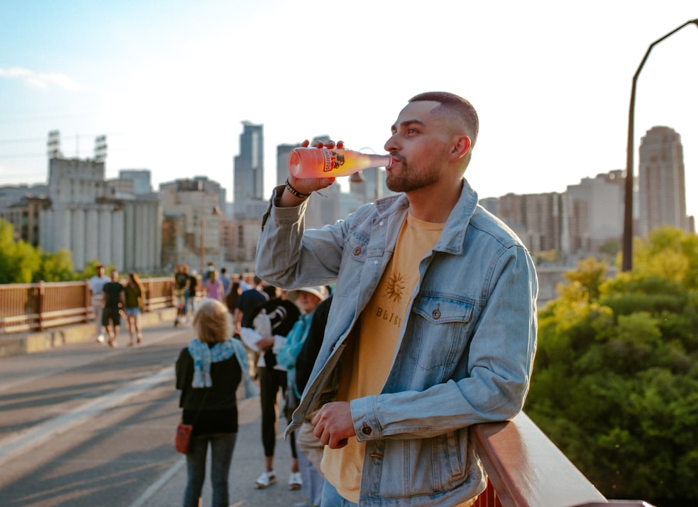 man in blue denim jacket holding brown ceramic mug