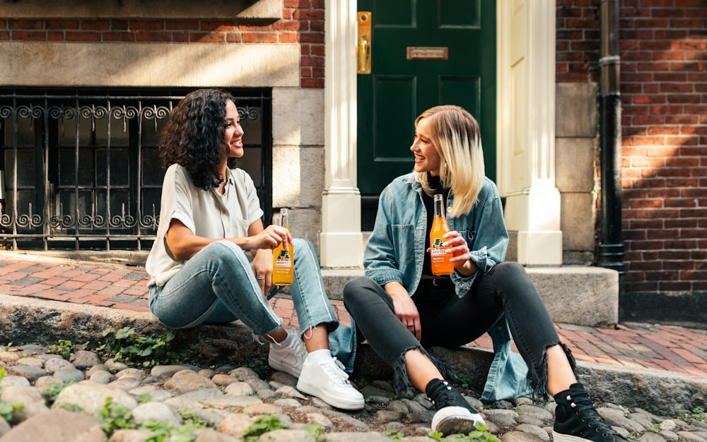 2 donne sedute sull'erba verde durante il giorno