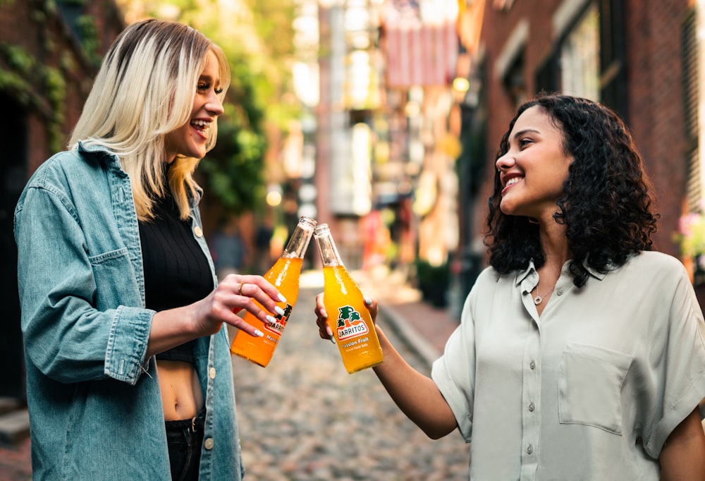 man in white button up shirt holding orange bottle beside woman in black cardigan holding orange