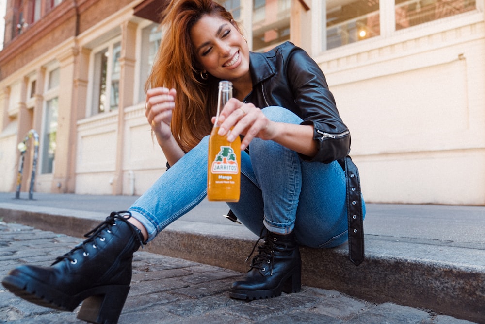 Frau in schwarzer Lederjacke mit orangefarbener Plastikflasche