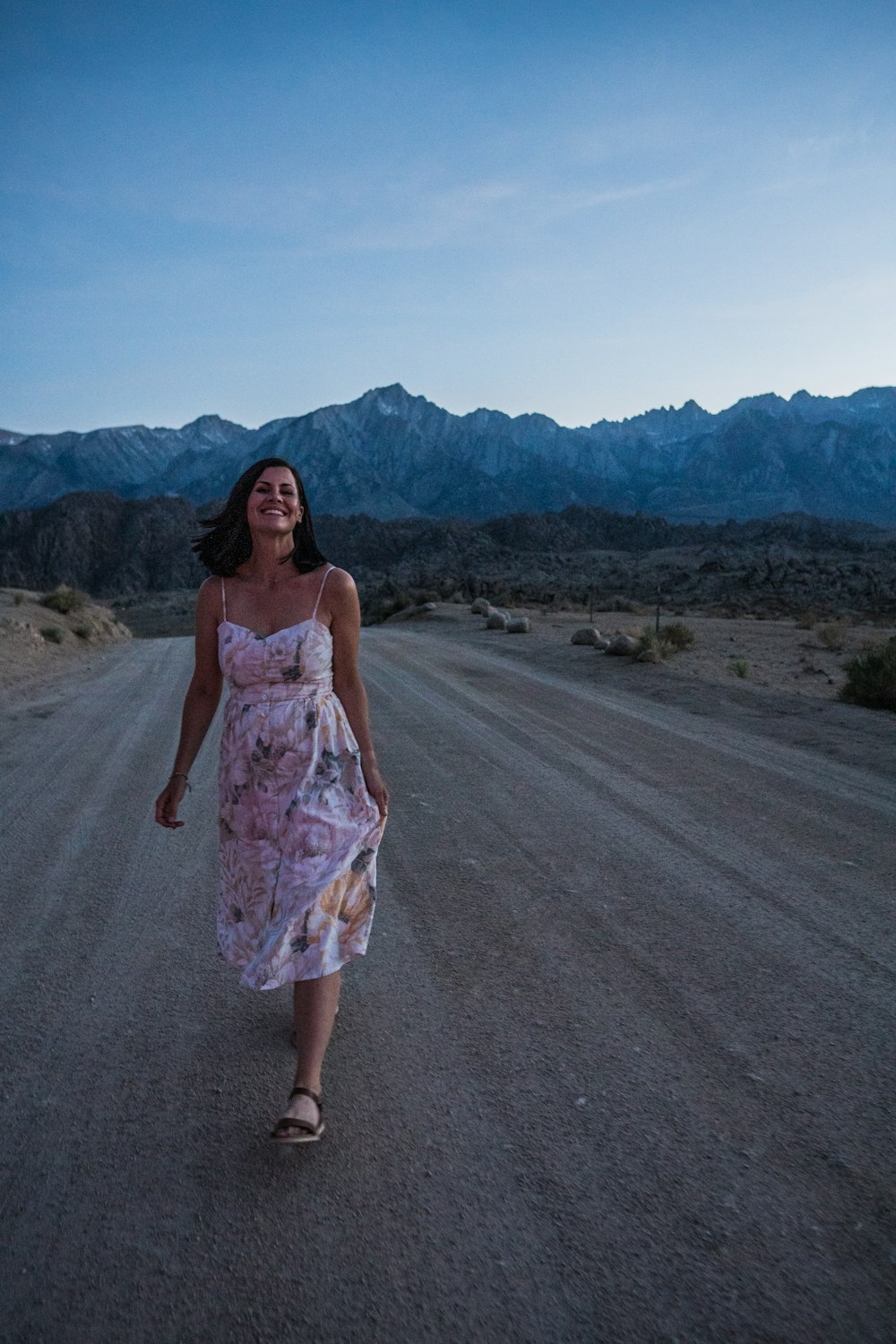 a woman in a dress walking down a dirt road