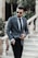 man in gray suit jacket and black pants wearing black sunglasses standing on gray concrete stairs