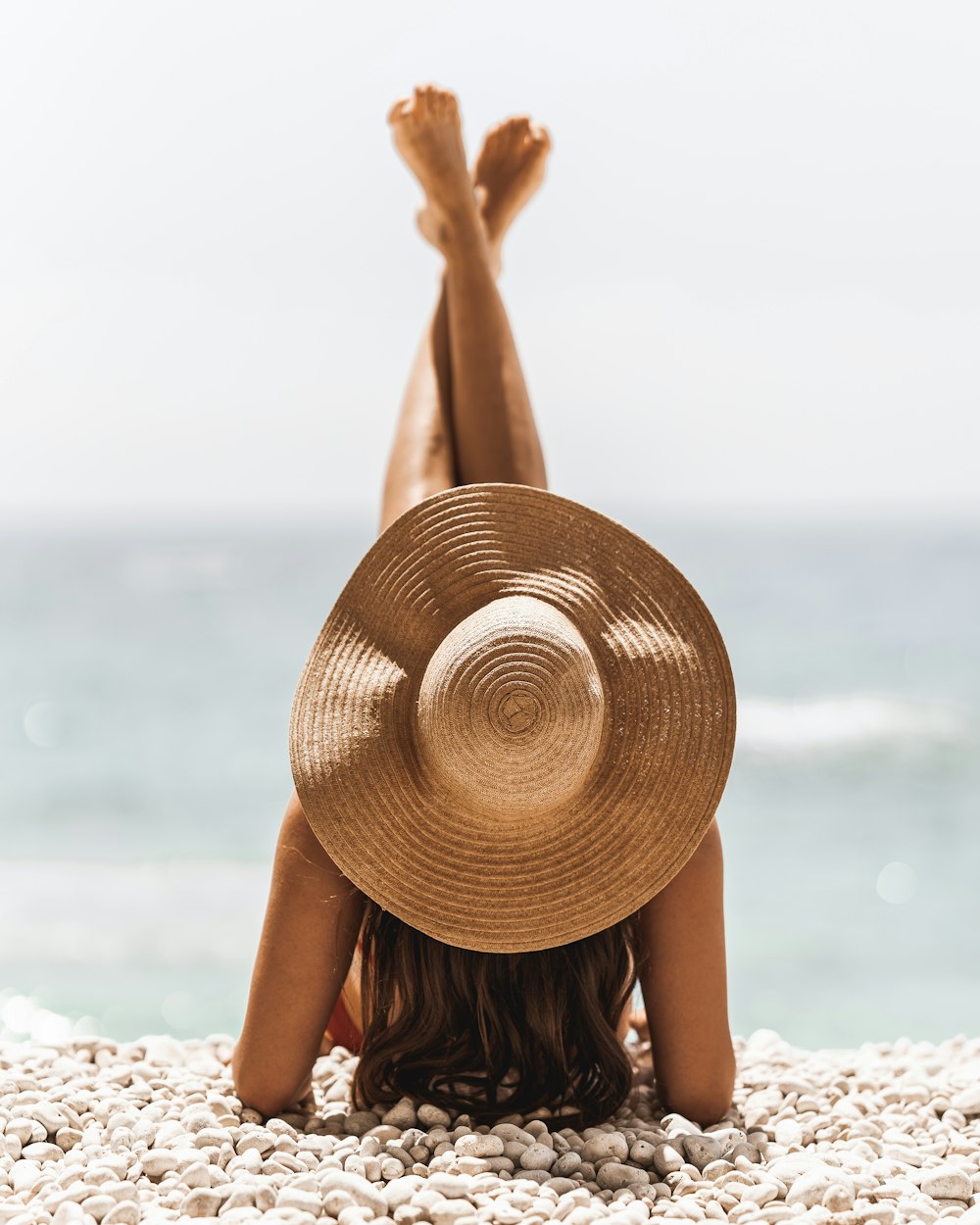 낮 동안 해변에 서 있는 갈색 태양 모자를 쓴 여자