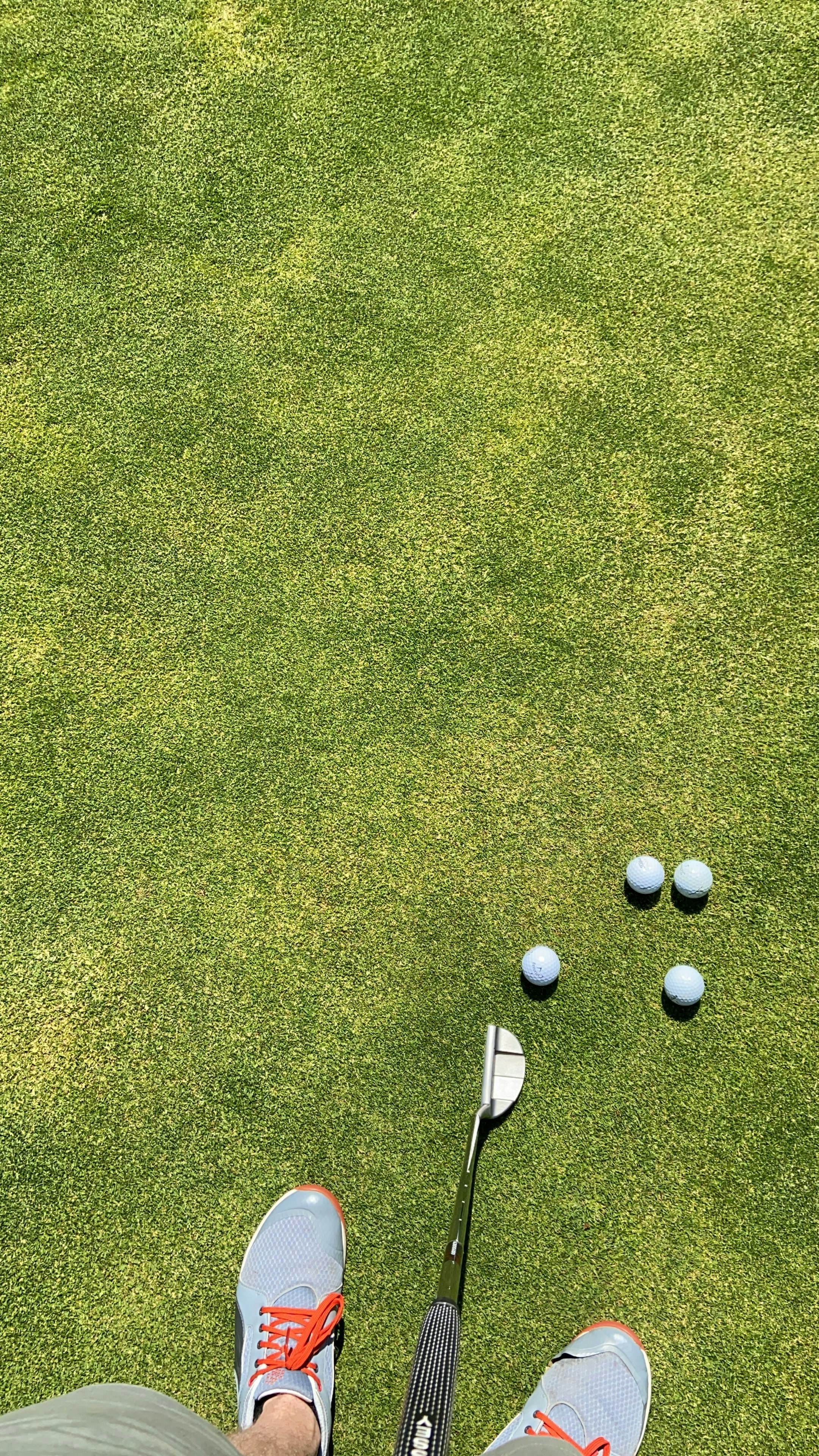 Mini golf putter and small green putting mat on a clean white bathroom floor, bright daylight
