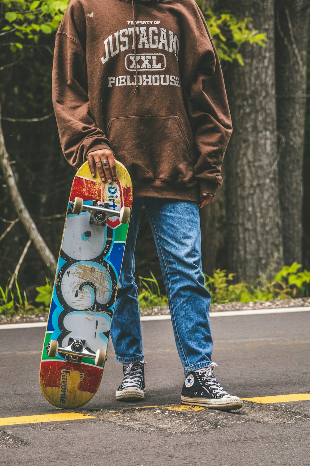 person in brown hoodie and blue denim jeans standing on road during daytime