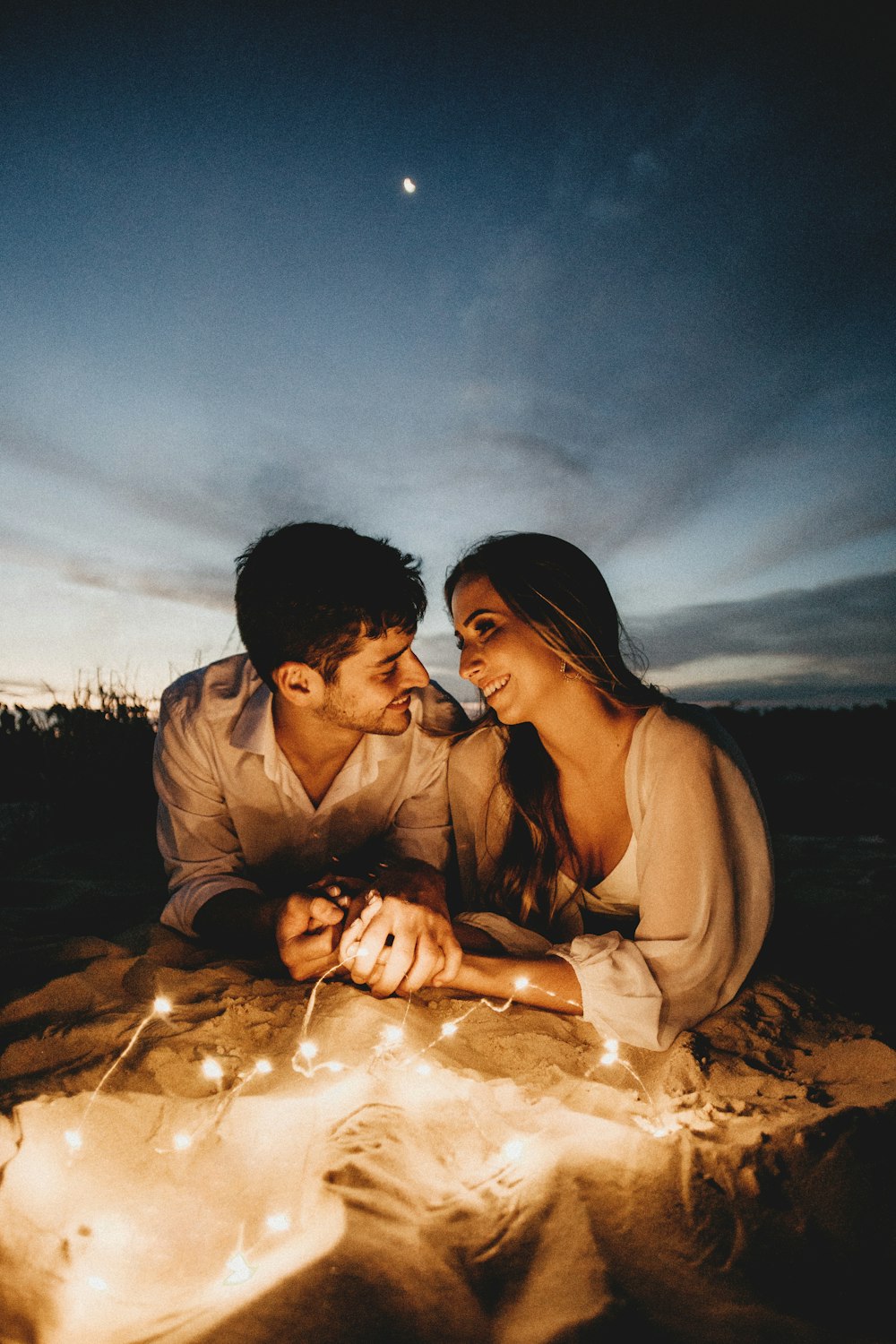 man and woman kissing on sand during daytime