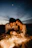 A couple enjoying a private beach dinner with lanterns glowing softly around them at twilight.