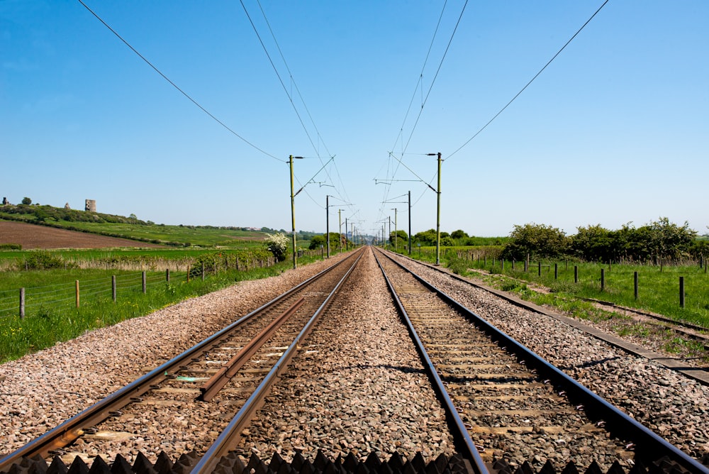 ferrovia marrone vicino al campo di erba verde durante il giorno