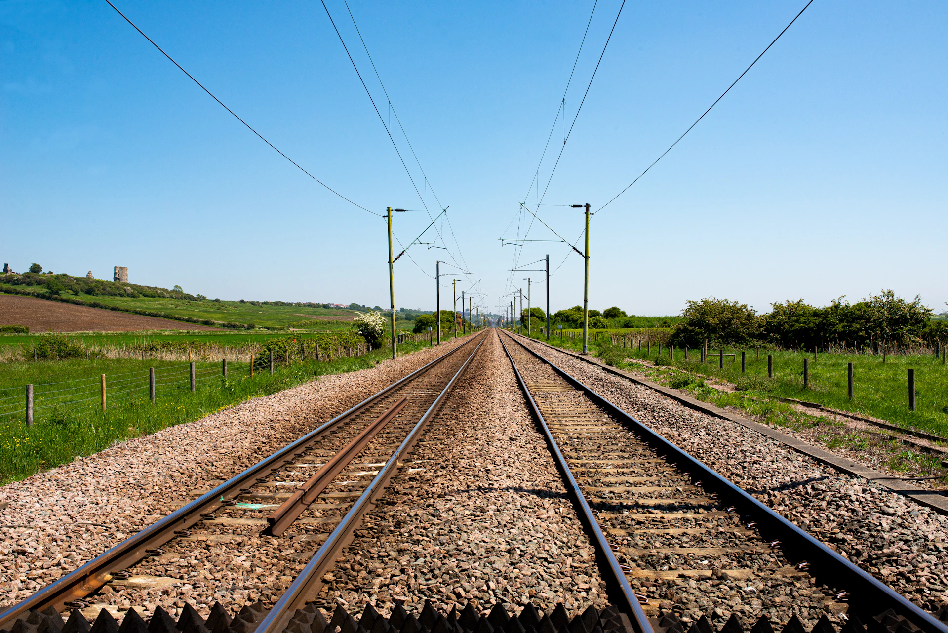 brown train rail near green grass field during daytime