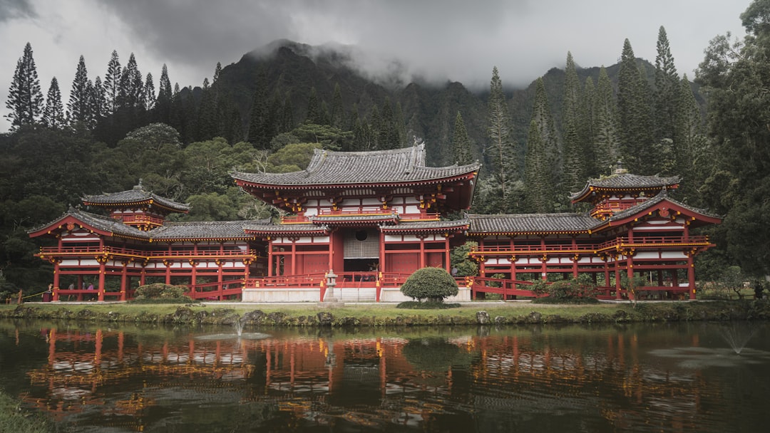 red and white temple near green trees and lake during daytime