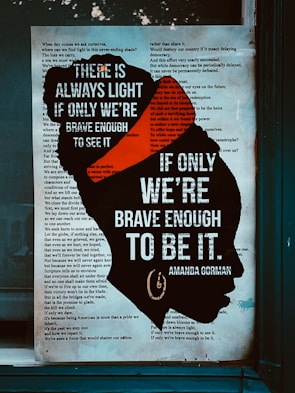 A text poster with a silhouette of a woman's head filled with text. Overlaid on the silhouette are bold white letters stating, 'There is always light if only we're brave enough to see it. If only we're brave enough to be it.' The rest of the poster displays an excerpt from a poem in the background.