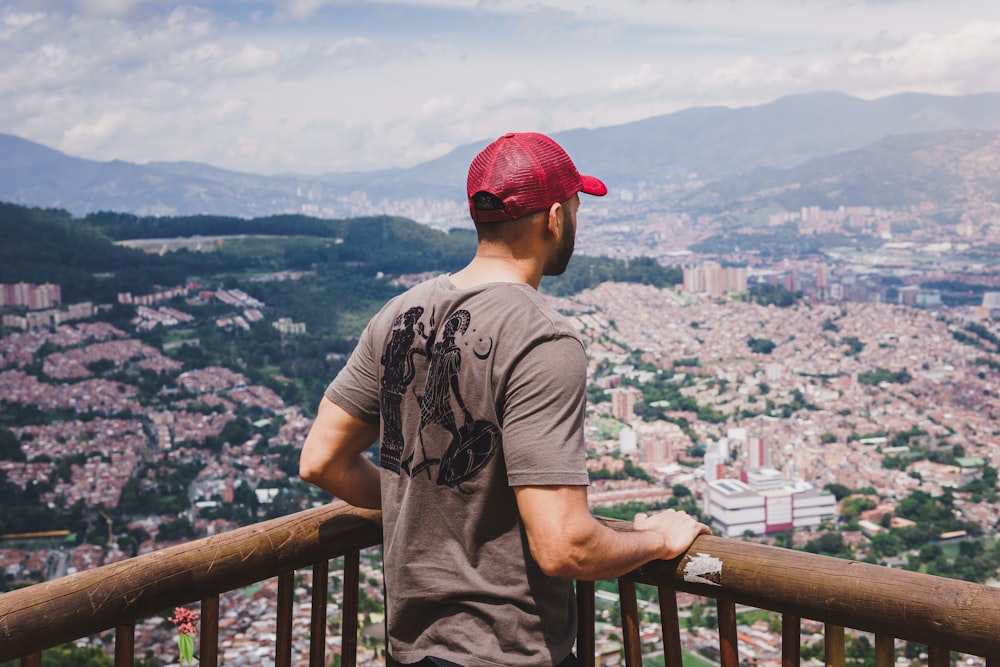 man in grey crew neck t-shirt standing on the edge of a building looking at on with with with