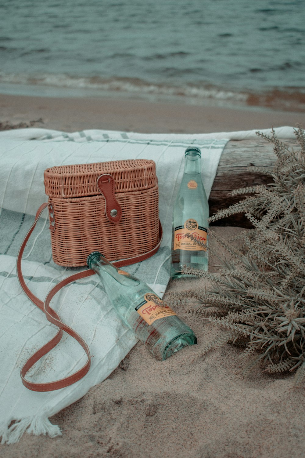 brown woven basket beside clear glass bottle on white textile