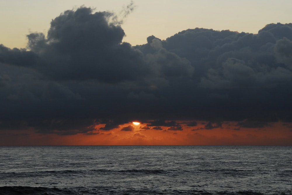 body of water under cloudy sky during sunset