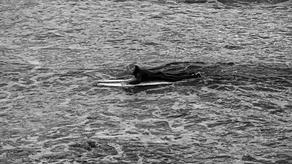 grayscale photo of woman surfing on water