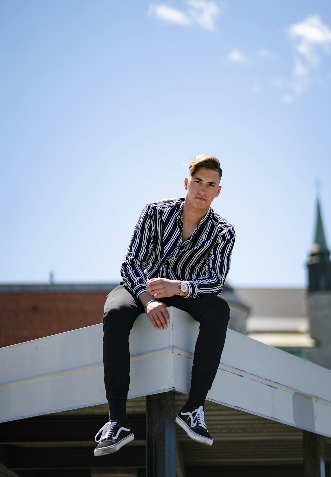 man in black and white striped long sleeve shirt and black pants sitting on white concrete