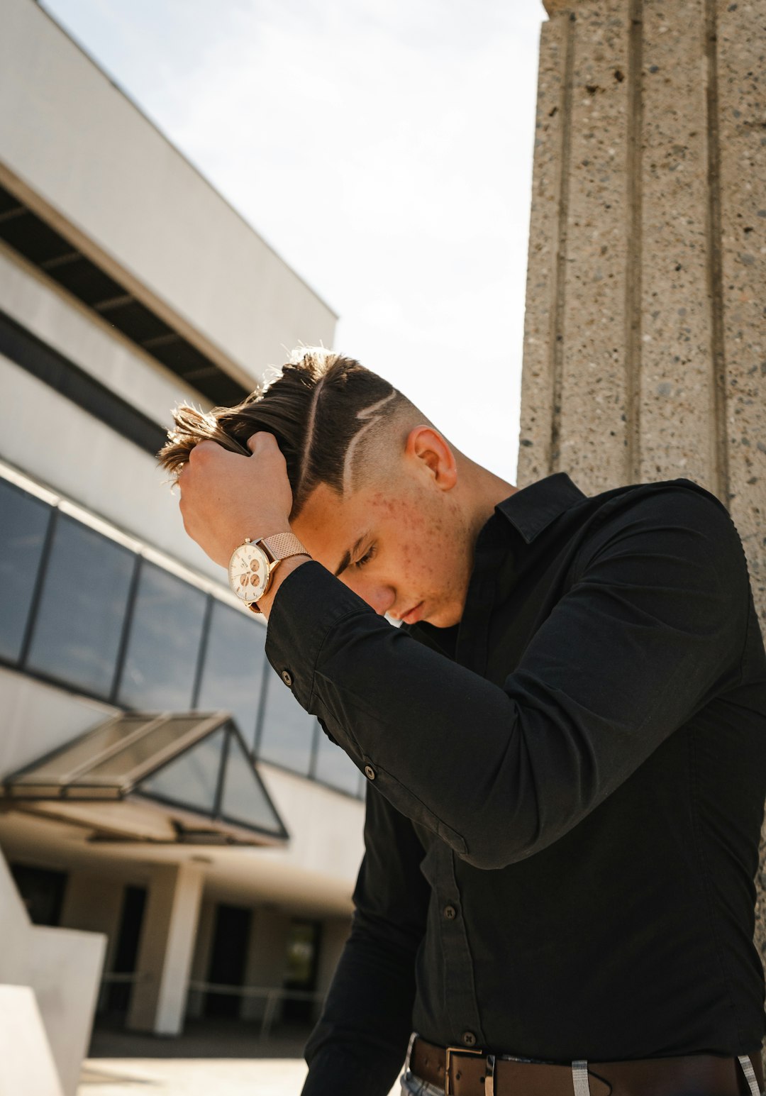 man in black long sleeve shirt leaning on brown concrete wall during daytime