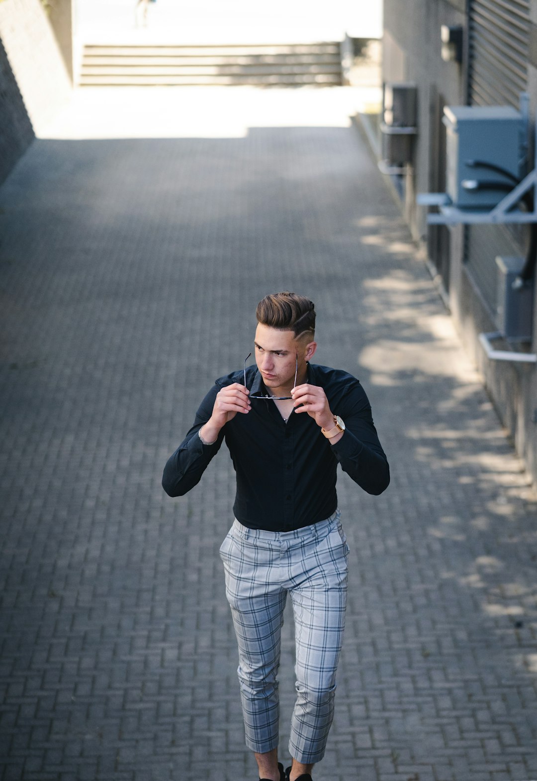 boy in black long sleeve shirt and white pants standing on gray concrete pavement