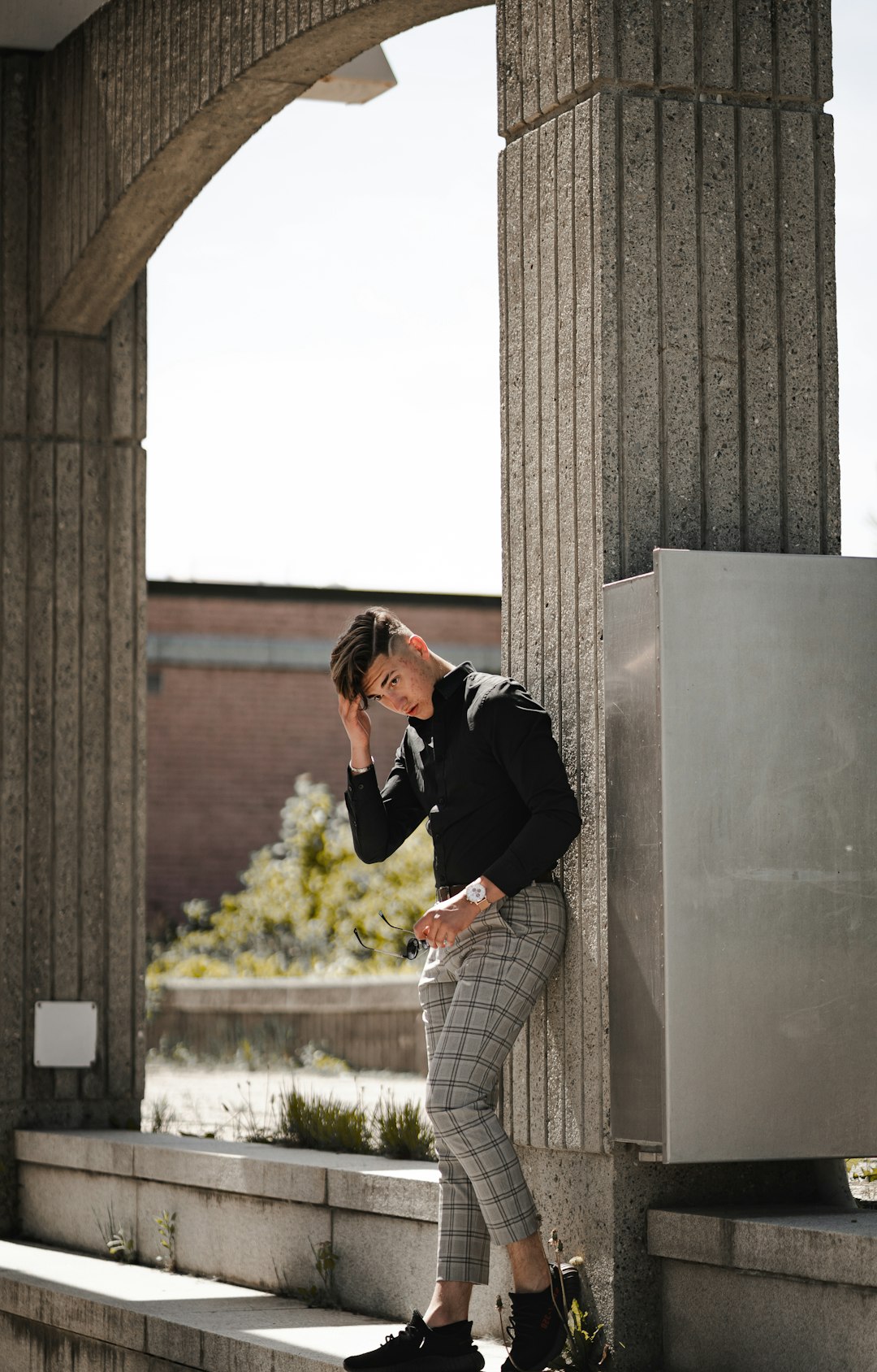 woman in black long sleeve shirt and gray pants leaning on gray concrete wall