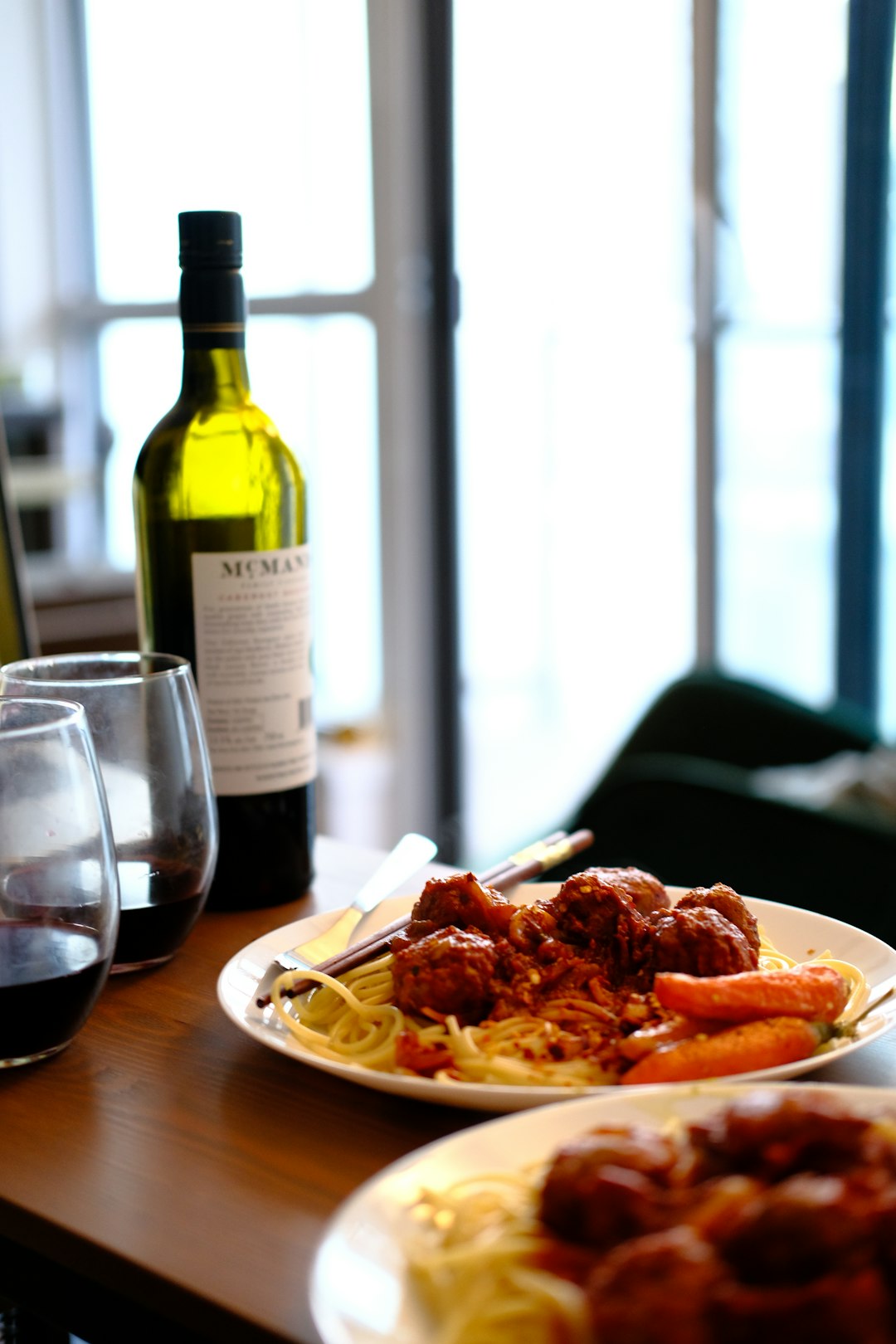 cooked food on white ceramic plate beside wine bottle on brown wooden table