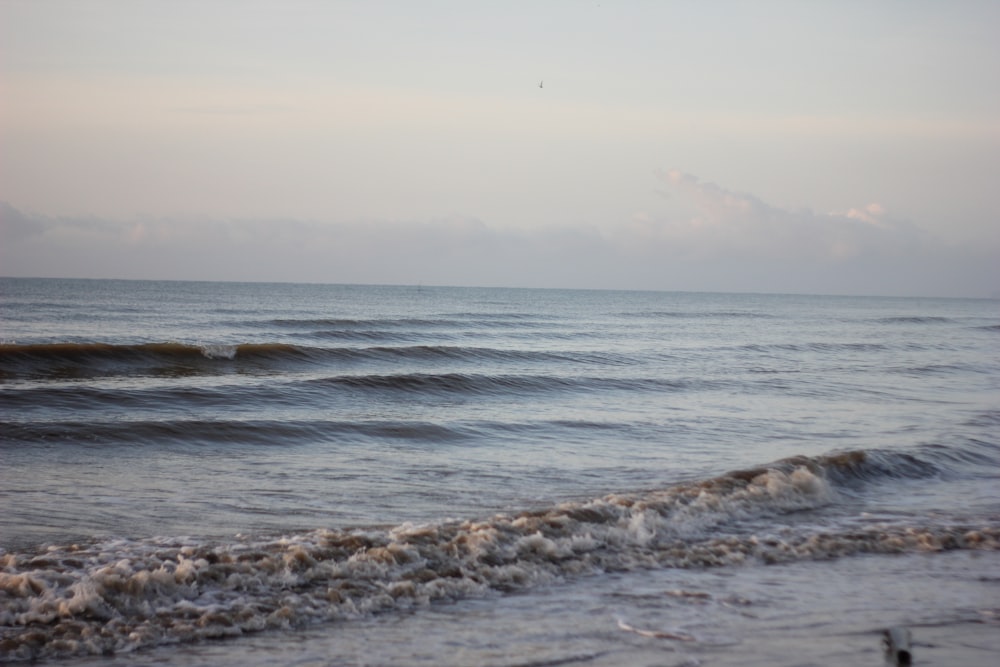 olas marinas rompiendo en la costa durante el día