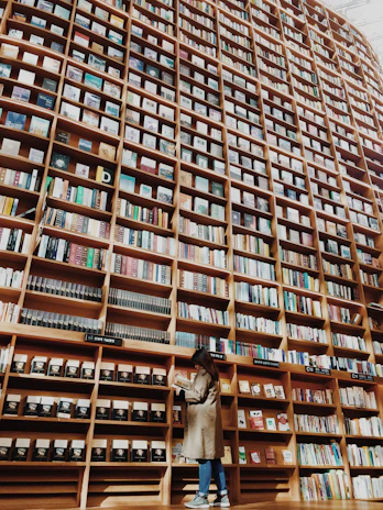 man in brown coat standing in front of brown wooden book shelf