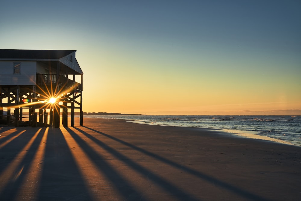 brown wooden house on beach during sunset