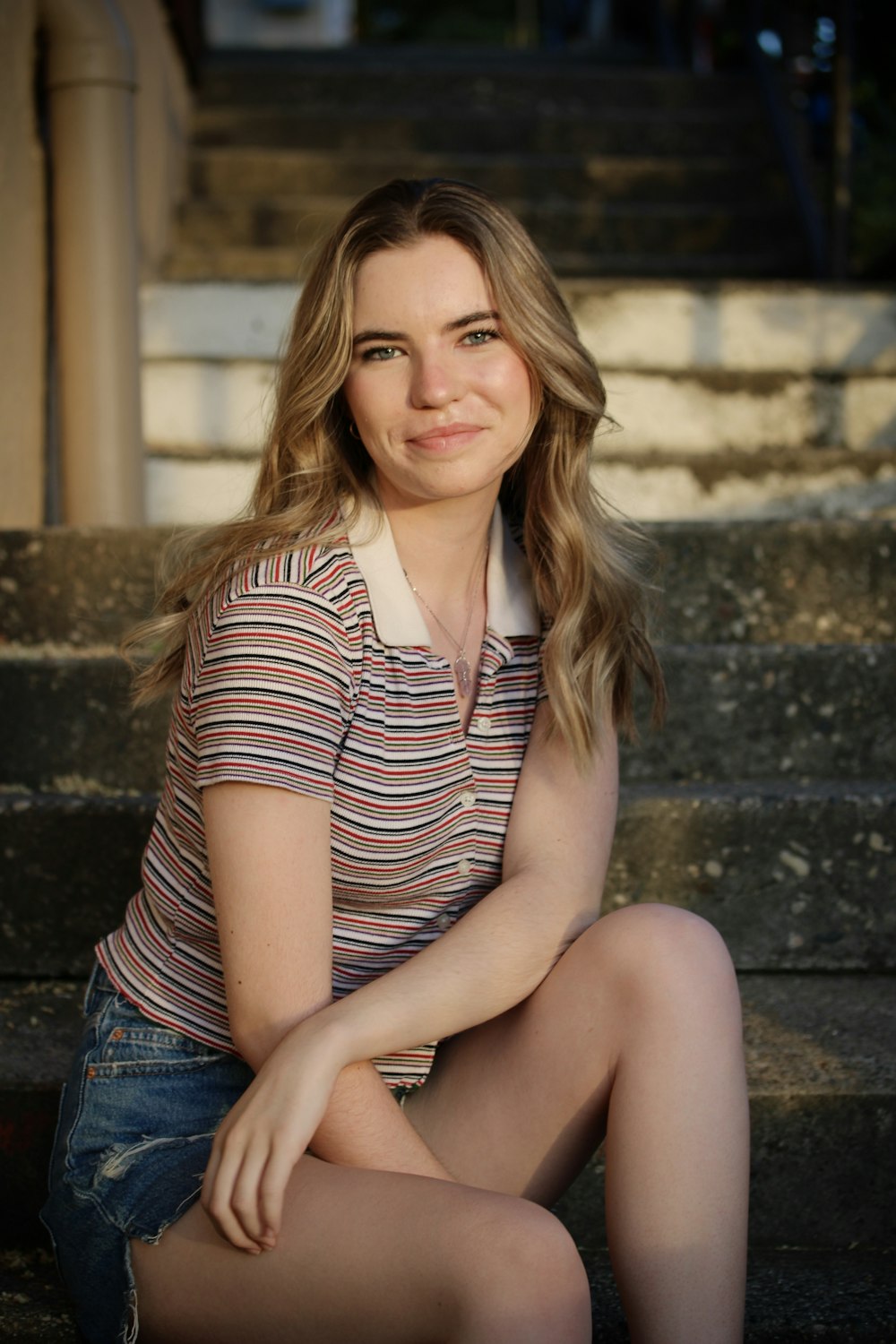 woman in black and white striped shirt and blue denim shorts sitting on concrete stairs